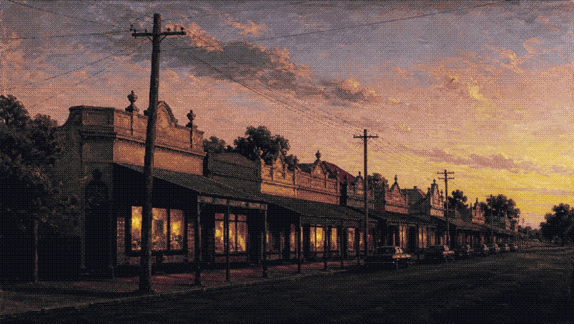 a row of suburban shopfronts at closing time, lights still on inside
